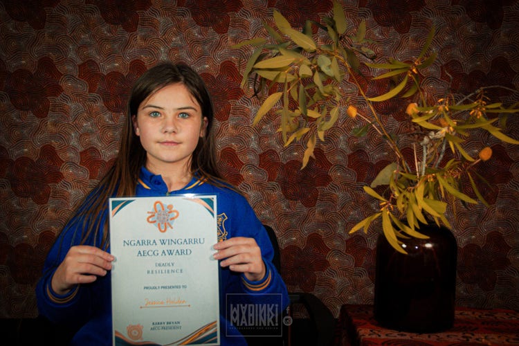 Female student receicing an award and smiling to camera
