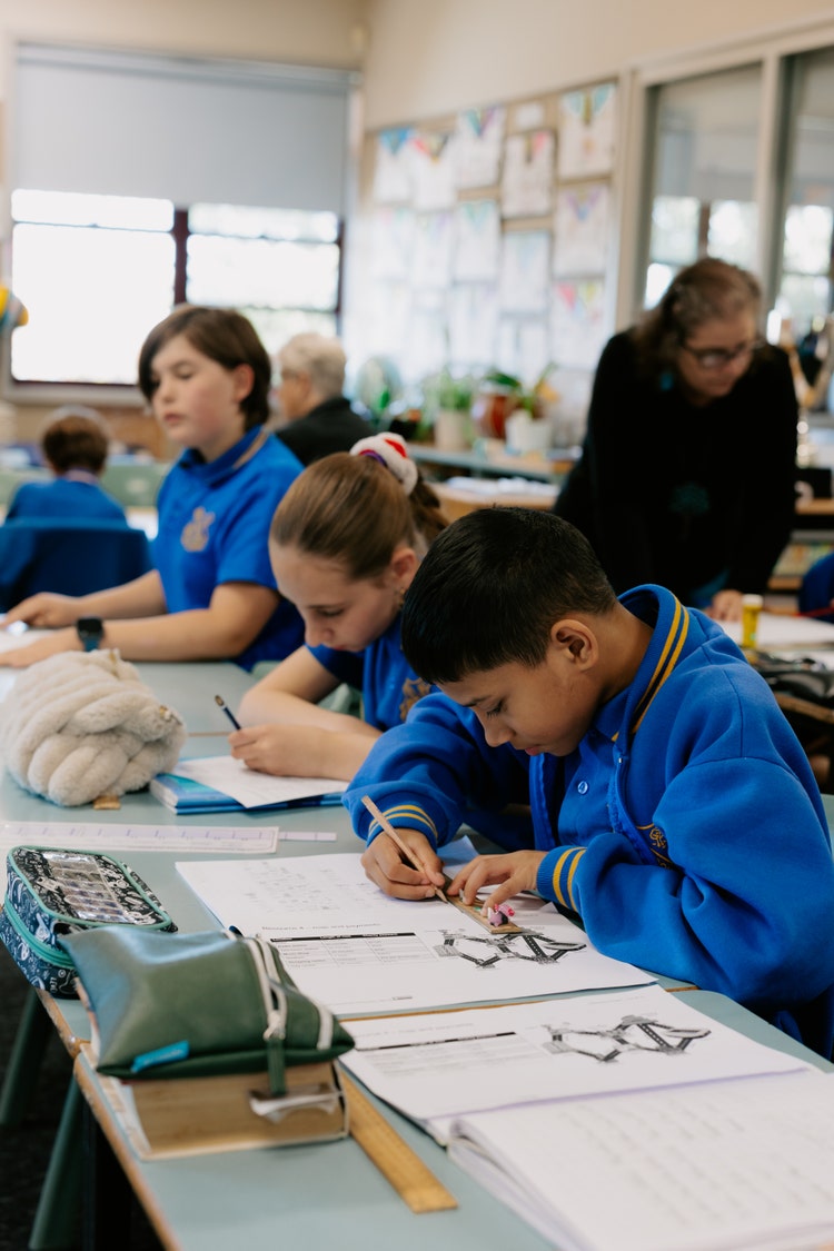 Female teacher helping a student with their work at a table in the classroom