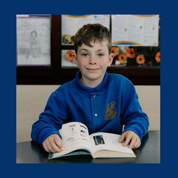 Young male student with a book open smiling to camera