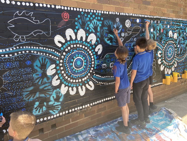 3 students painting an Indigenous mural using blue colours
