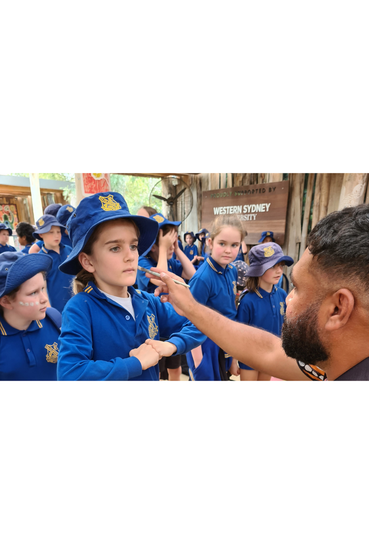 A male student having his face painted by Aboriginal elder