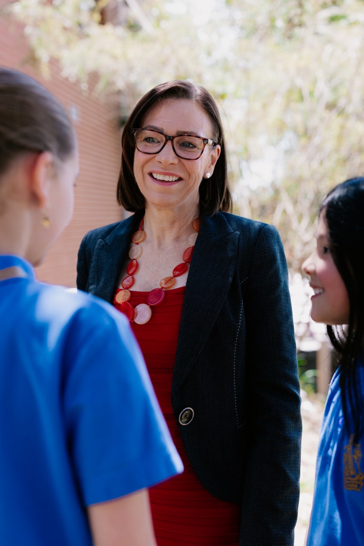 Female principal smiling and talking to two older female students
