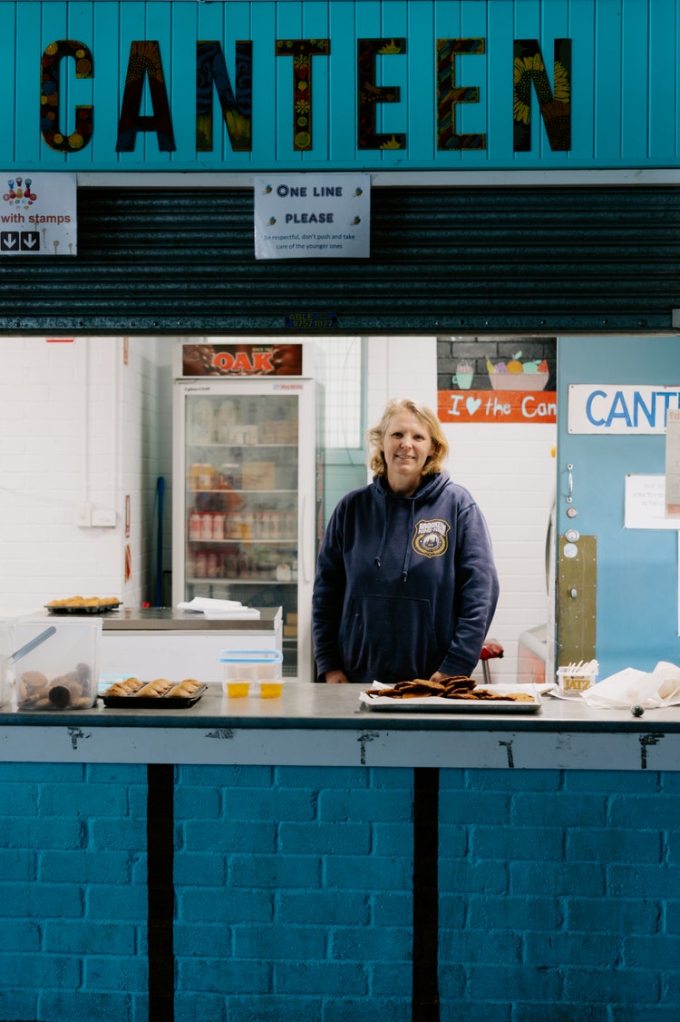 Female adult smiling to camera while standing at canteen counter