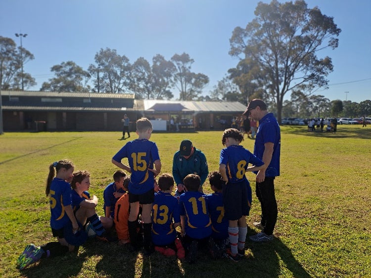 A group of students in sports uniform huddled before a soccer game