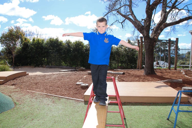 Young male student looking to camera while walking on balance beam
